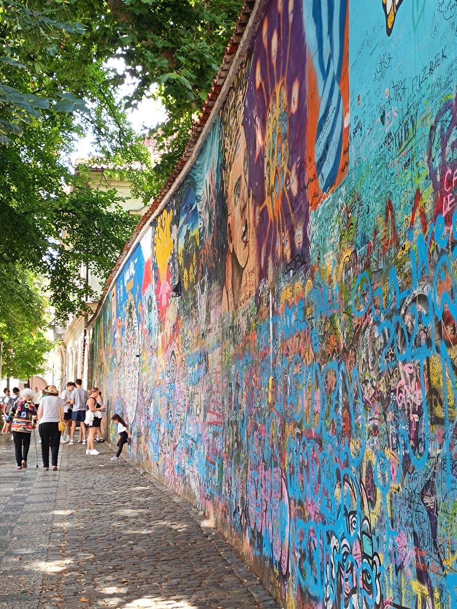 Tourists walking by the John Lennon Wall Prague