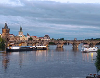 Prague river cruise on the Vltava River at sunset with Charles Bridge, sightseeing boats and the historic Old Town skyline.